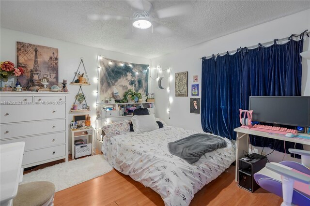 bedroom with a textured ceiling, ceiling fan, and wood finished floors