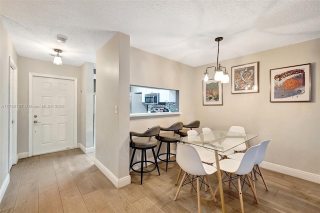dining room featuring baseboards, wood finished floors, and a textured ceiling