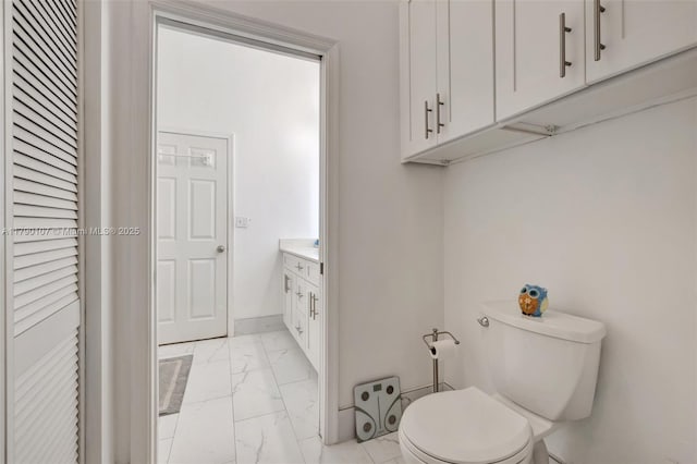 half bath with baseboards, marble finish floor, vanity, and toilet