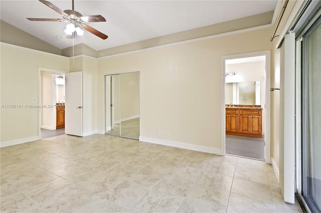 unfurnished bedroom featuring baseboards, ensuite bath, light tile patterned floors, and vaulted ceiling