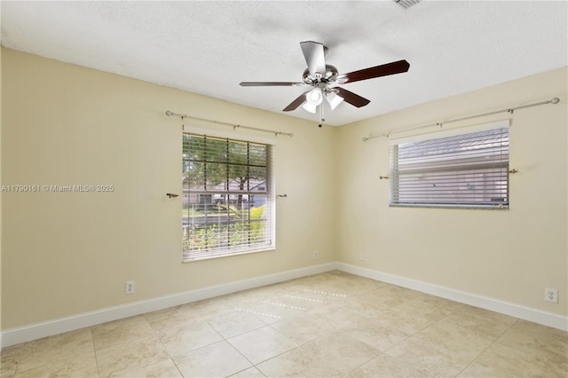 tiled empty room with baseboards, ceiling fan, and a textured ceiling