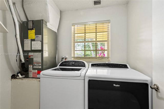 washroom with heating unit, visible vents, laundry area, and washing machine and clothes dryer