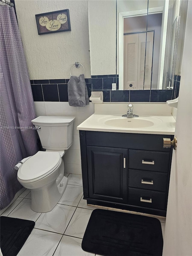 9401 NW 14th Ct Unit 224, Pembroke Pines, FL 33024 - full bathroom with marble finish floor, toilet, vanity, tile walls, and wainscoting