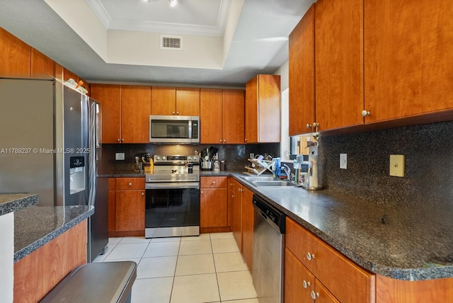 kitchen with appliances with stainless steel finishes, a raised ceiling, a sink, crown molding, and tasteful backsplash