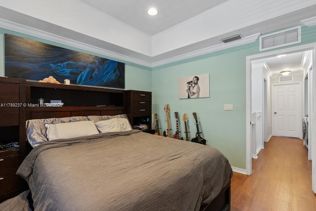 bedroom featuring wood finished floors, baseboards, a tray ceiling, and recessed lighting