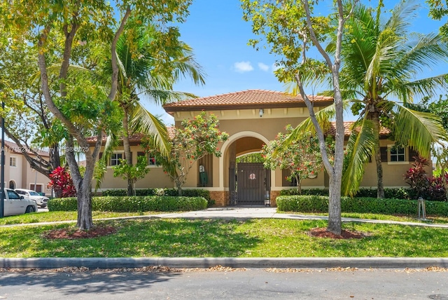 mediterranean / spanish home featuring stucco siding, a tiled roof, and a front yard