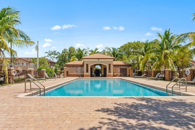 community pool with a patio area and fence
