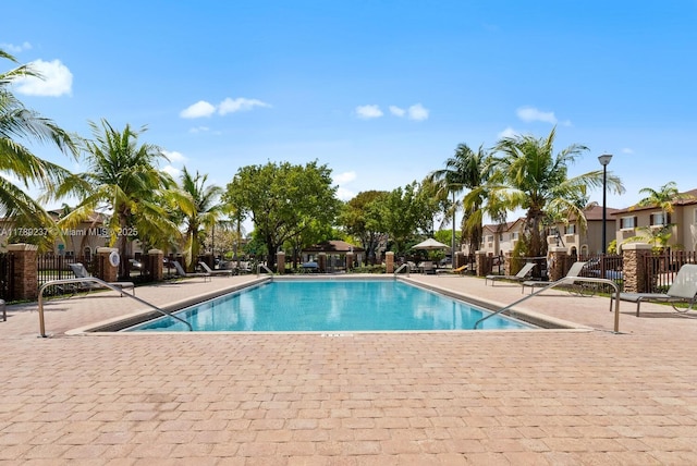 community pool featuring a patio area, fence, and a residential view