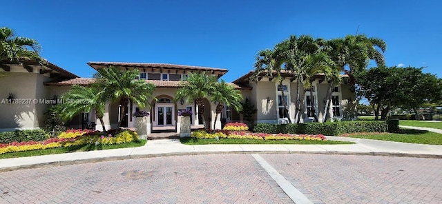 mediterranean / spanish-style home featuring stucco siding, a tile roof, and french doors
