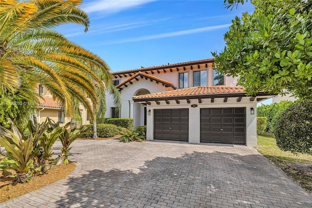 mediterranean / spanish-style house featuring stucco siding, decorative driveway, and a tile roof