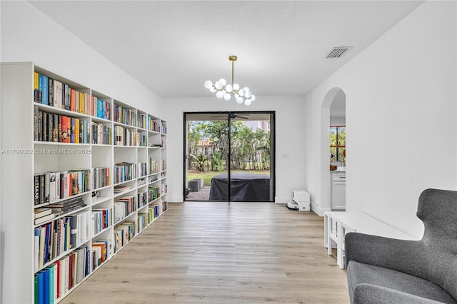 sitting room featuring arched walkways, visible vents, an inviting chandelier, and wood finished floors
