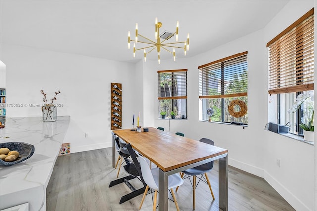 dining space with light wood finished floors, a chandelier, and baseboards