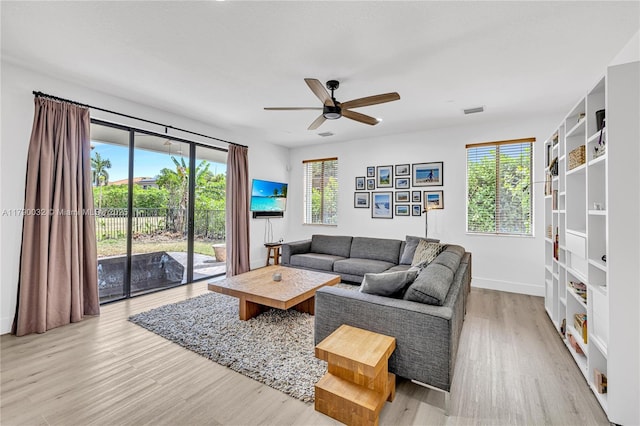 living area with visible vents, a ceiling fan, light wood finished floors, and baseboards