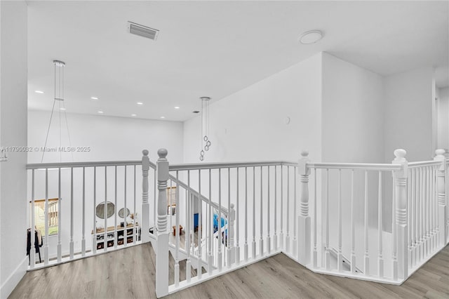 hall featuring visible vents, wood finished floors, an upstairs landing, and recessed lighting