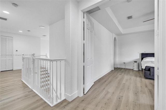 hallway featuring wood finished floors, baseboards, visible vents, and arched walkways