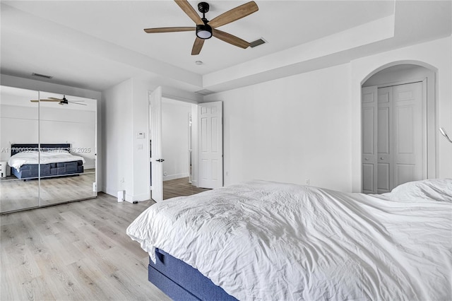 bedroom featuring arched walkways, visible vents, a closet, and wood finished floors