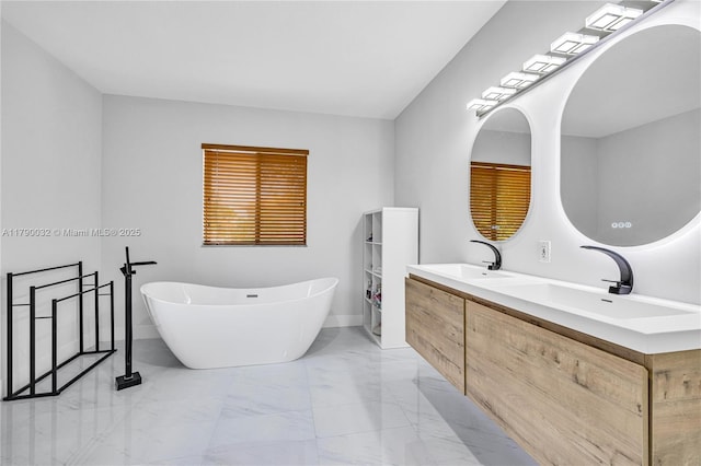 bathroom featuring marble finish floor, a sink, double vanity, and a soaking tub