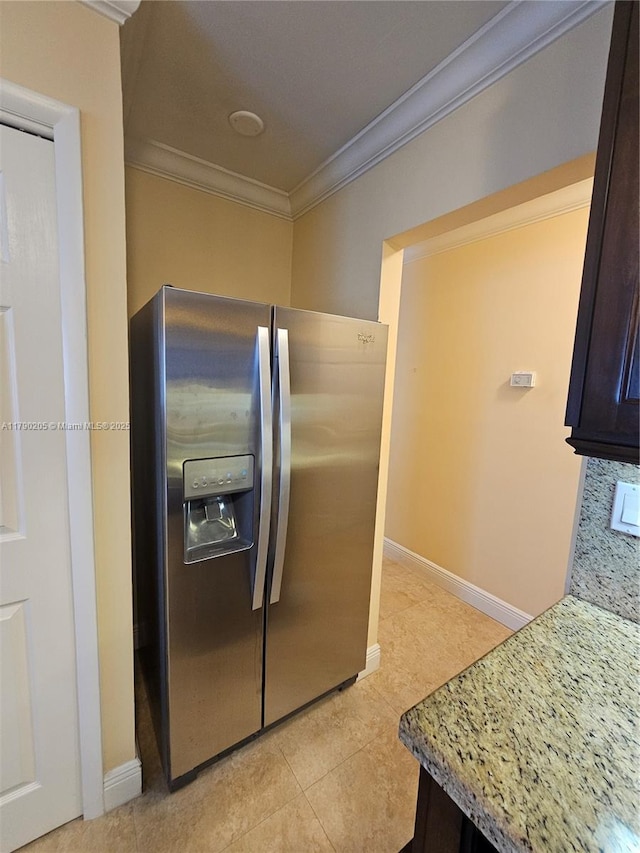 kitchen with dark brown cabinets, light tile patterned floors, crown molding, baseboards, and stainless steel fridge