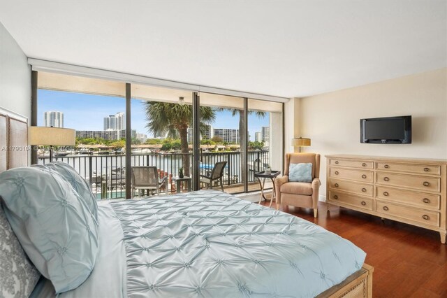 bedroom with floor to ceiling windows, wood finished floors, access to exterior, and a water view