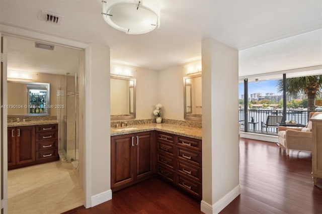 interior space featuring a sink, baseboards, dark wood-style flooring, light stone countertops, and visible vents