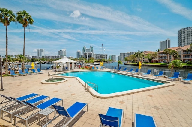 pool with fence, a city view, a water view, and a patio
