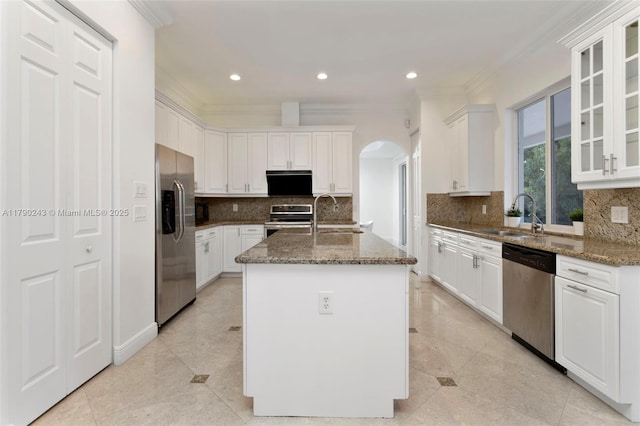 15355 SW 34th St, Davie, FL 33331 - kitchen featuring stainless steel appliances, arched walkways, crown molding, dark stone countertops, and a kitchen island with sink