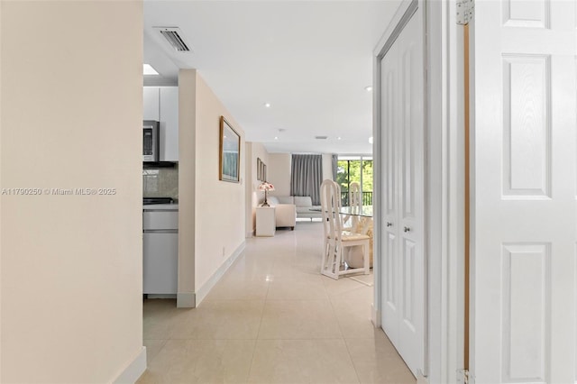 corridor featuring light tile patterned floors, recessed lighting, visible vents, and baseboards