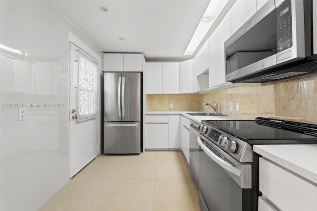 kitchen featuring a sink, appliances with stainless steel finishes, decorative backsplash, and white cabinetry
