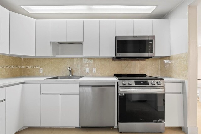 kitchen featuring white cabinetry, tasteful backsplash, a sink, stainless steel appliances, and light countertops