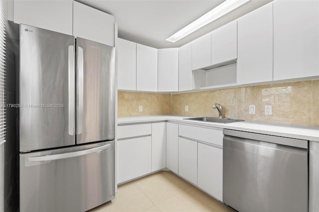kitchen featuring a sink, decorative backsplash, light tile patterned flooring, light countertops, and appliances with stainless steel finishes