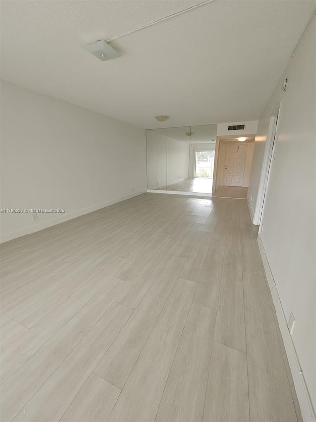 empty room with visible vents, baseboards, and light wood-style floors