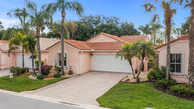 mediterranean / spanish-style home featuring a garage, stucco siding, decorative driveway, and a tiled roof
