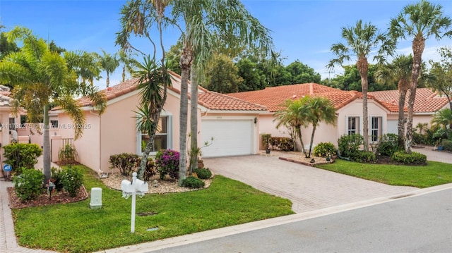 mediterranean / spanish home featuring a front lawn, a garage, decorative driveway, a tiled roof, and stucco siding