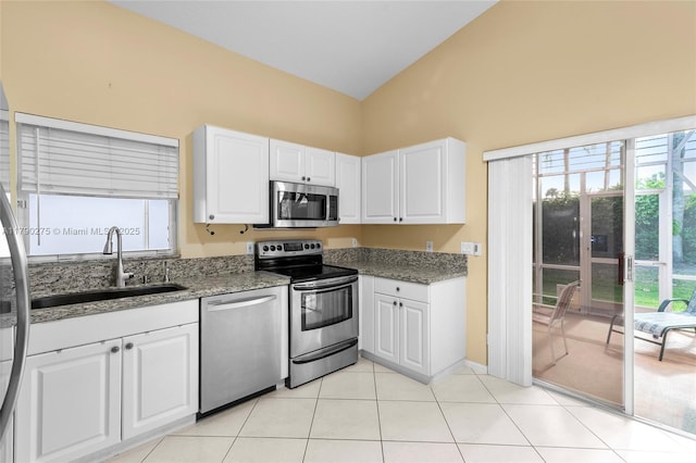 kitchen with appliances with stainless steel finishes, light stone counters, high vaulted ceiling, and a sink