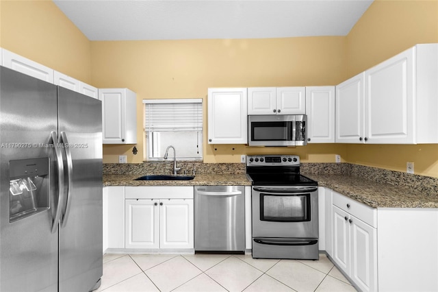 kitchen with light tile patterned floors, a sink, white cabinetry, and stainless steel appliances