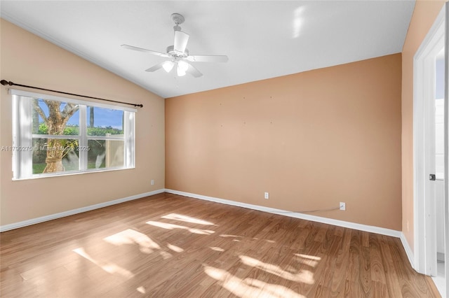 empty room featuring lofted ceiling, wood finished floors, a ceiling fan, and baseboards