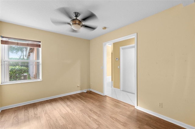 empty room with ceiling fan, light wood finished floors, and baseboards
