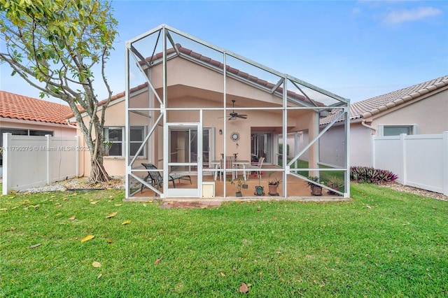 back of property with stucco siding, fence, ceiling fan, a patio, and a lawn