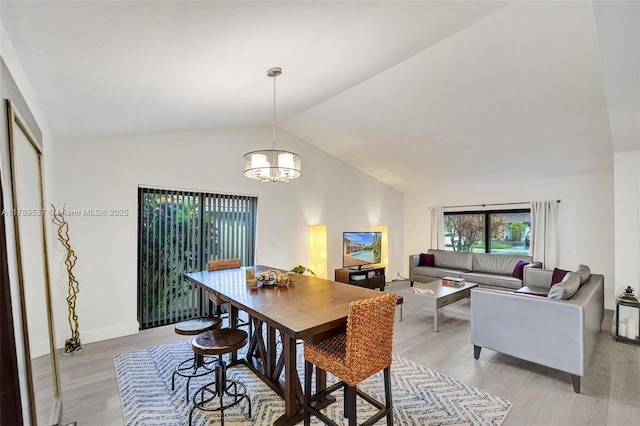 dining room featuring vaulted ceiling, light wood-type flooring, a chandelier, and baseboards