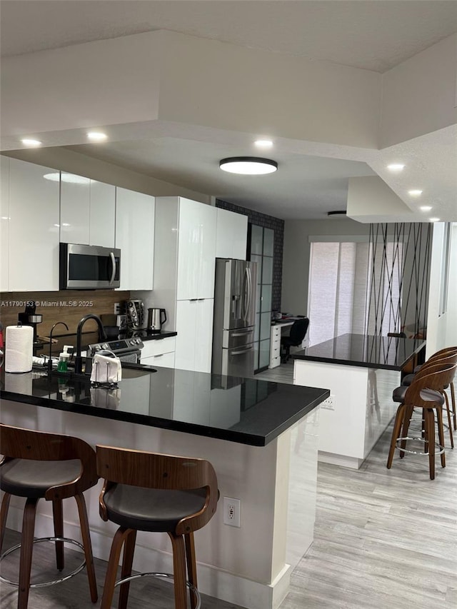 10730 NW 66 Unit 101, Doral, FL 33178 - kitchen featuring stainless steel appliances, modern cabinets, a peninsula, a kitchen bar, and dark countertops