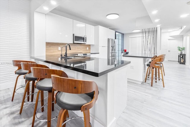 10730 NW 66 Unit 101, Doral, FL 33178 - kitchen featuring stainless steel appliances, a breakfast bar area, a peninsula, dark countertops, and white cabinets