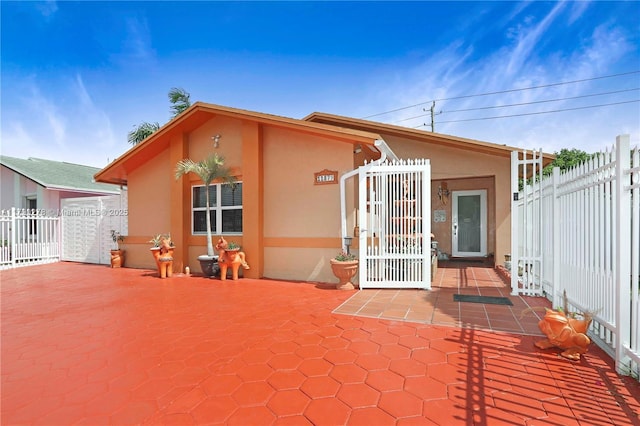 back of property with fence, a gate, a patio area, and stucco siding