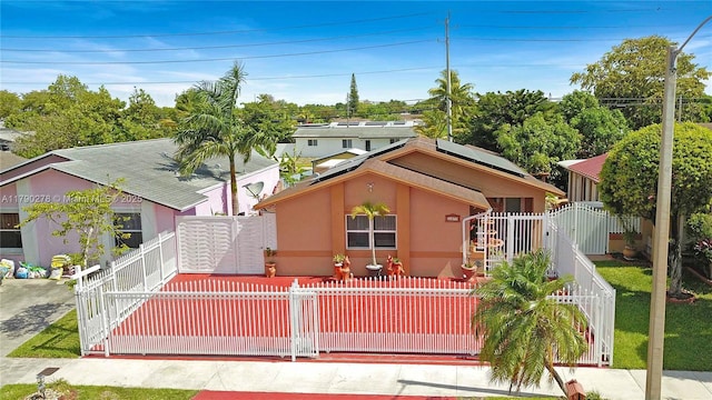 view of front of home featuring a gate, stucco siding, solar panels, and a fenced front yard