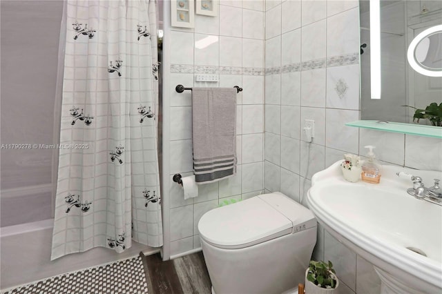 full bath with a sink, shower / tub combo, toilet, and tile walls
