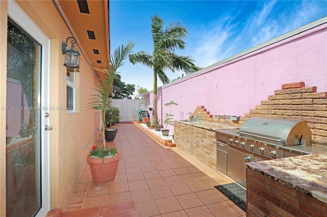 view of patio / terrace with exterior kitchen, fence, and a grill