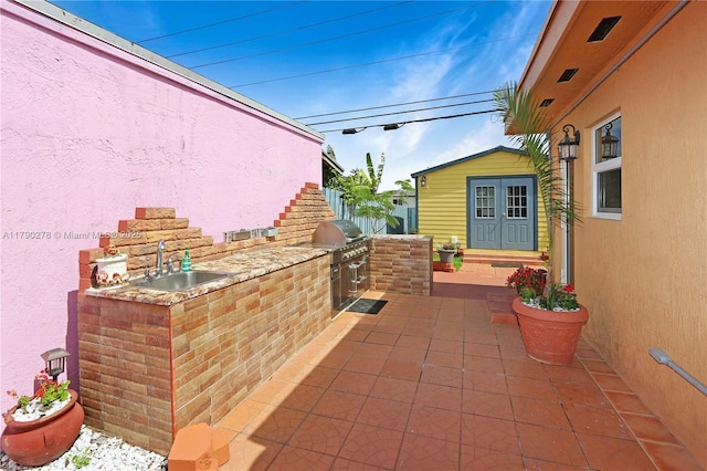 view of patio featuring a sink, an outdoor structure, a grill, and area for grilling