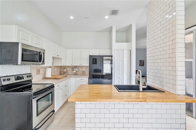 13995 S Cypress Cove Cir, Davie, FL 33325 - kitchen with stainless steel appliances, butcher block counters, light tile patterned flooring, white cabinetry, and recessed lighting