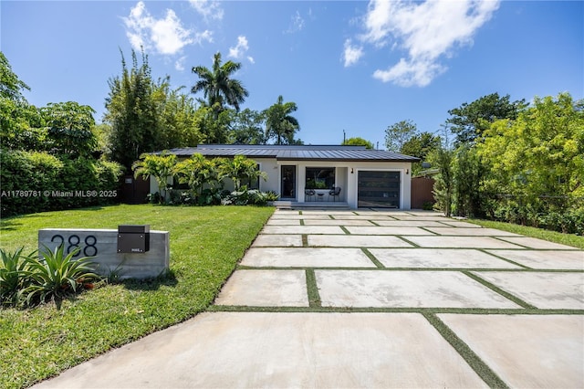 exterior space with a standing seam roof, metal roof, a lawn, driveway, and an attached garage