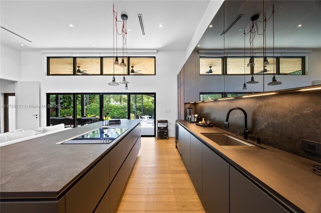 288 NE 117th St, Miami, FL 33161 - kitchen featuring a high ceiling, dark countertops, light wood-style flooring, black electric cooktop, and recessed lighting