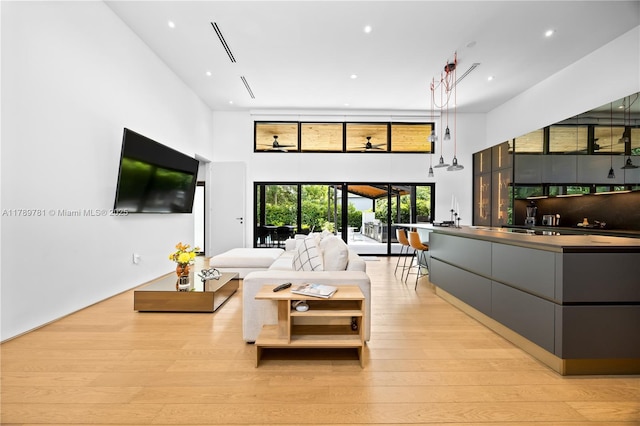 living area with a towering ceiling, recessed lighting, and light wood-type flooring